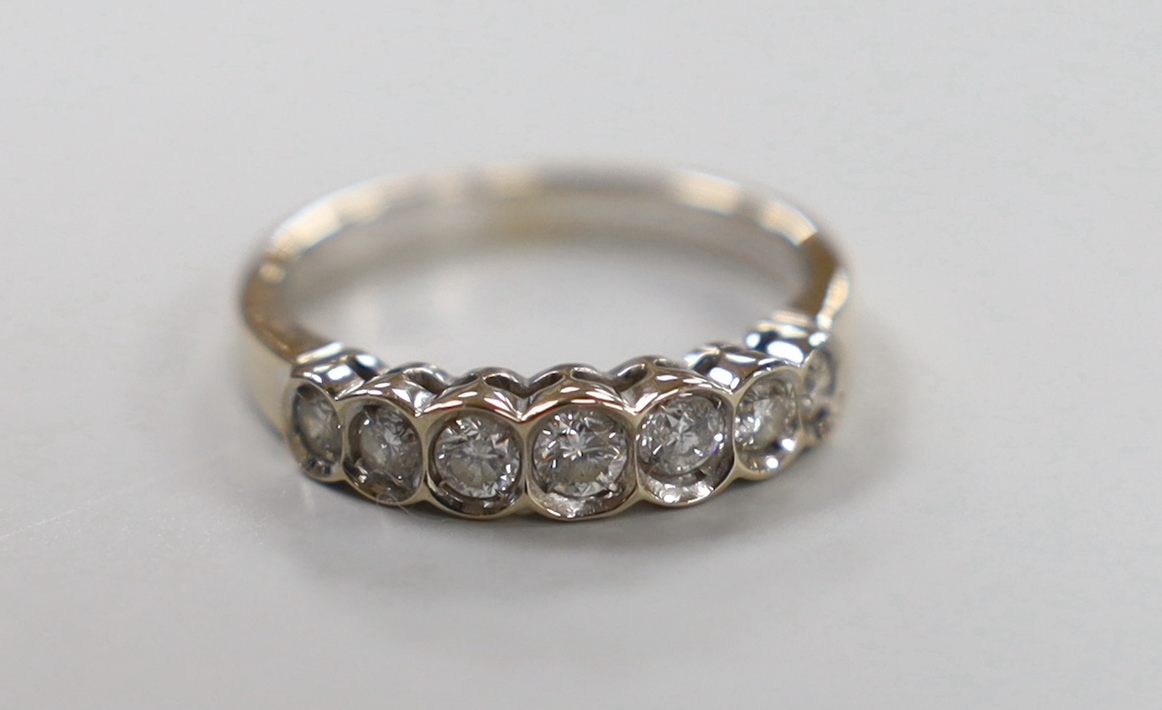 A modern white metal and graduated seven stone diamond set half hoop ring, size L, gross weight 3.2 grams.